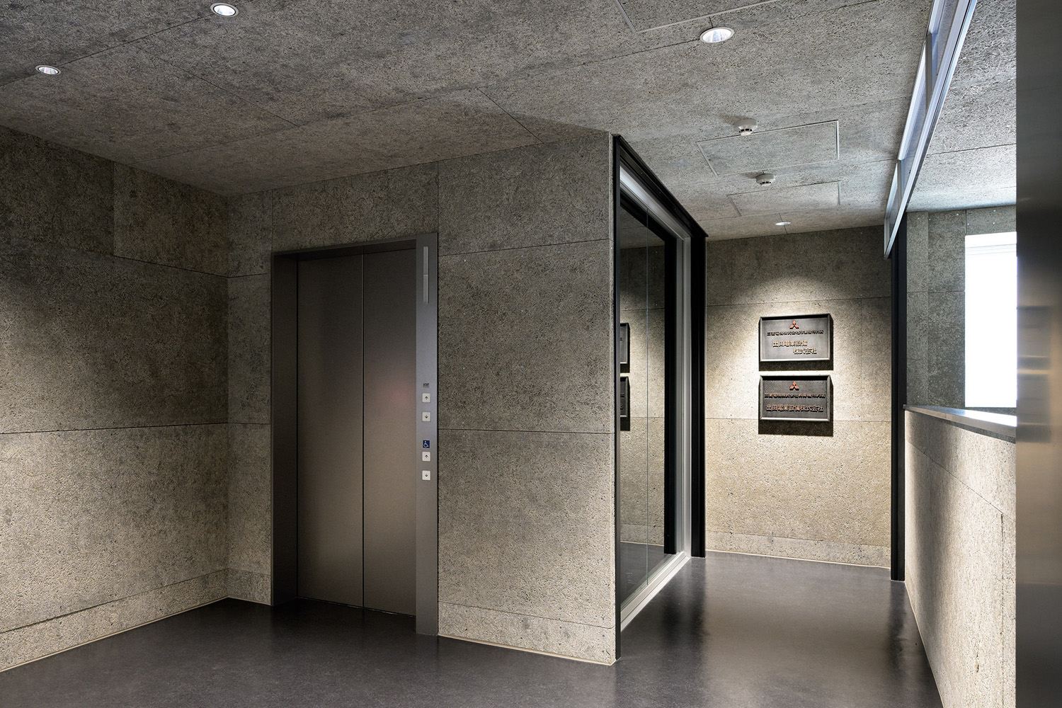 2階エントランス。エレベーターの扉および三方枠にはステンレスのバイブレーション仕上げを採用。上質感を高めることで、屋内デザインとの親和性を向上させている（エントランス：2階）