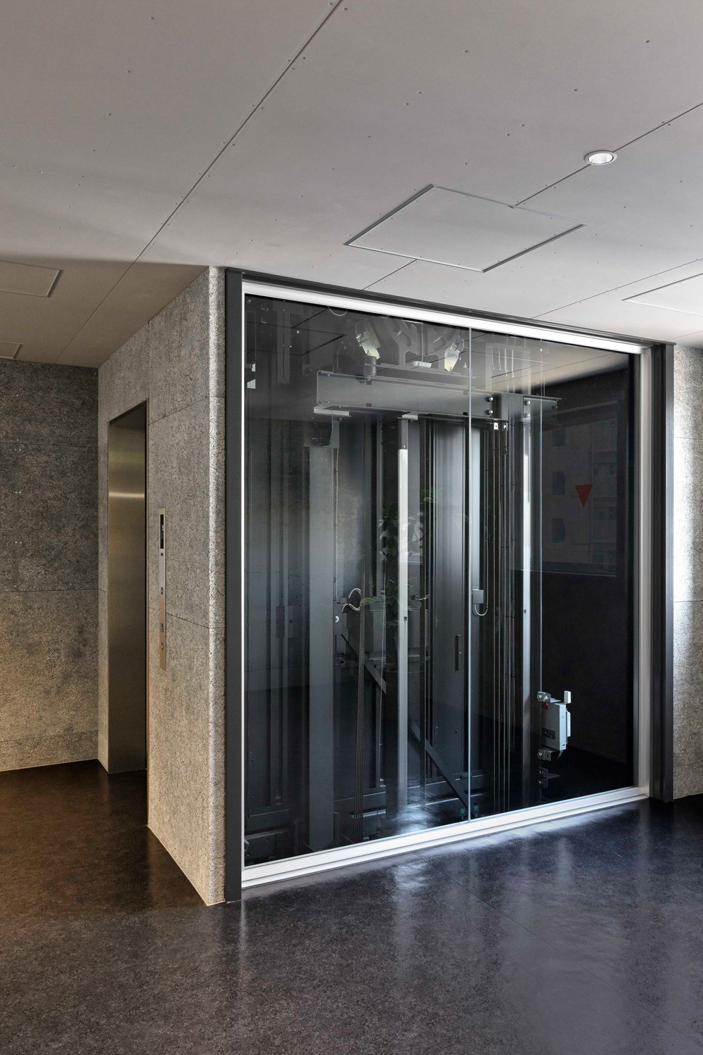 エレベーター側面は1階、2階と同じくガラス張りのエレベーターシャフトを採用。昇降路内は塗装が施されている（スカイラウンジ エントランス：5階）