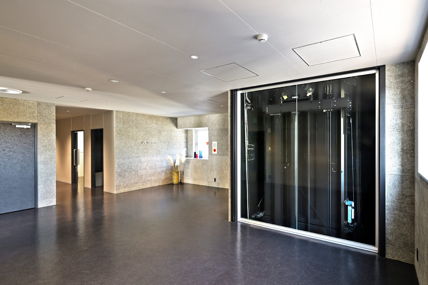 最上階のスカイラウンジは、来訪者を迎え入れるもてなしの場として利用されている。エントランスは開放感的であり、その中でエレベーターの存在感がいっそう際立っている（スカイラウンジ エントランス：5階）