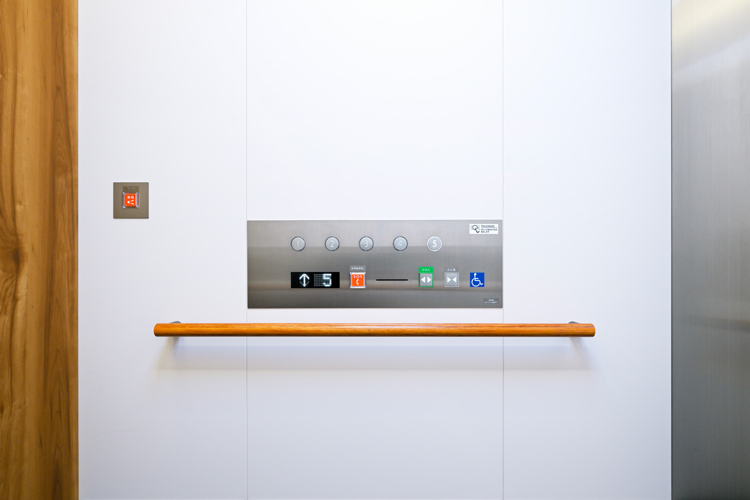 快適空間エレベーターならではの木目調のマテリアルと、シャープな質感のステンレス、さらには洗練された白い壁面が調和した操作盤周辺のデザイン（エレベーター：かご室内）