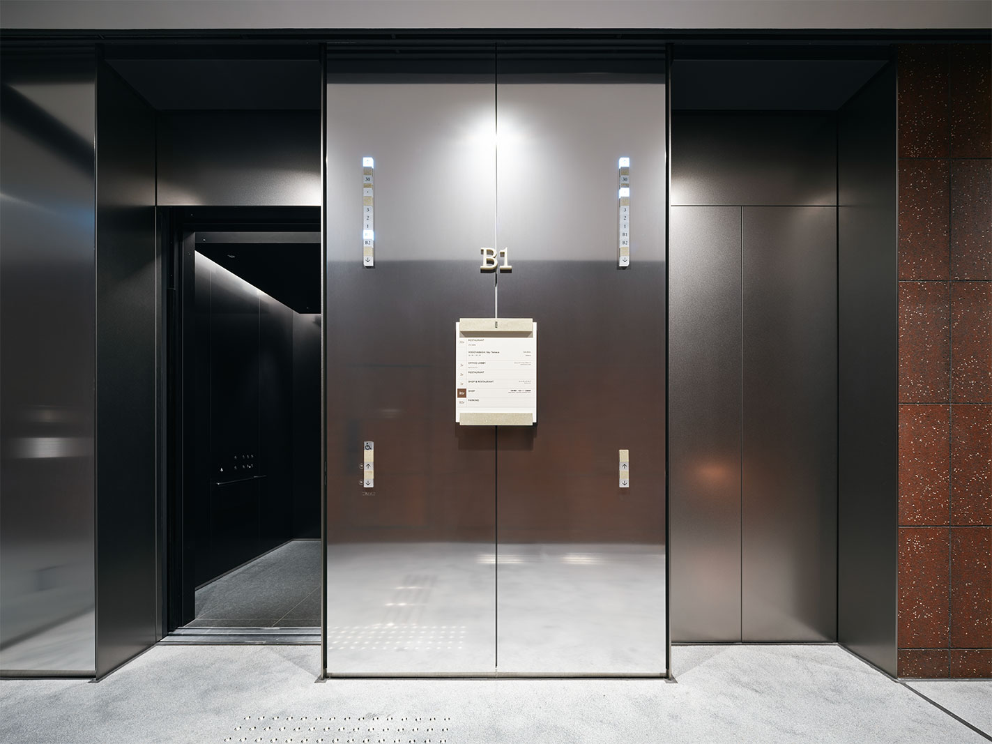 30階の展望台「淀屋橋スカイテラス」へと至る地下1階エレベーター乗場。立体的に構成された扉に、ステンレスバイブレーションを採用している。